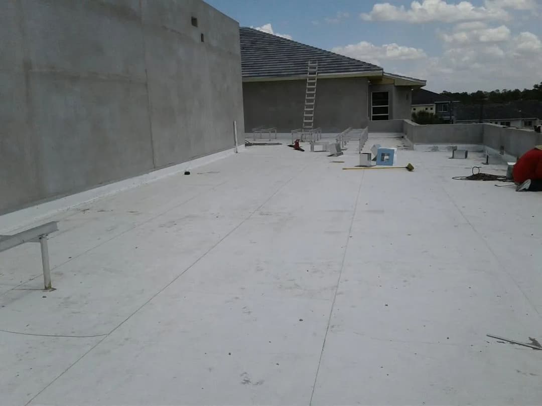 Flat rooftop with a ladder, construction materials, and a clear sky in the background.