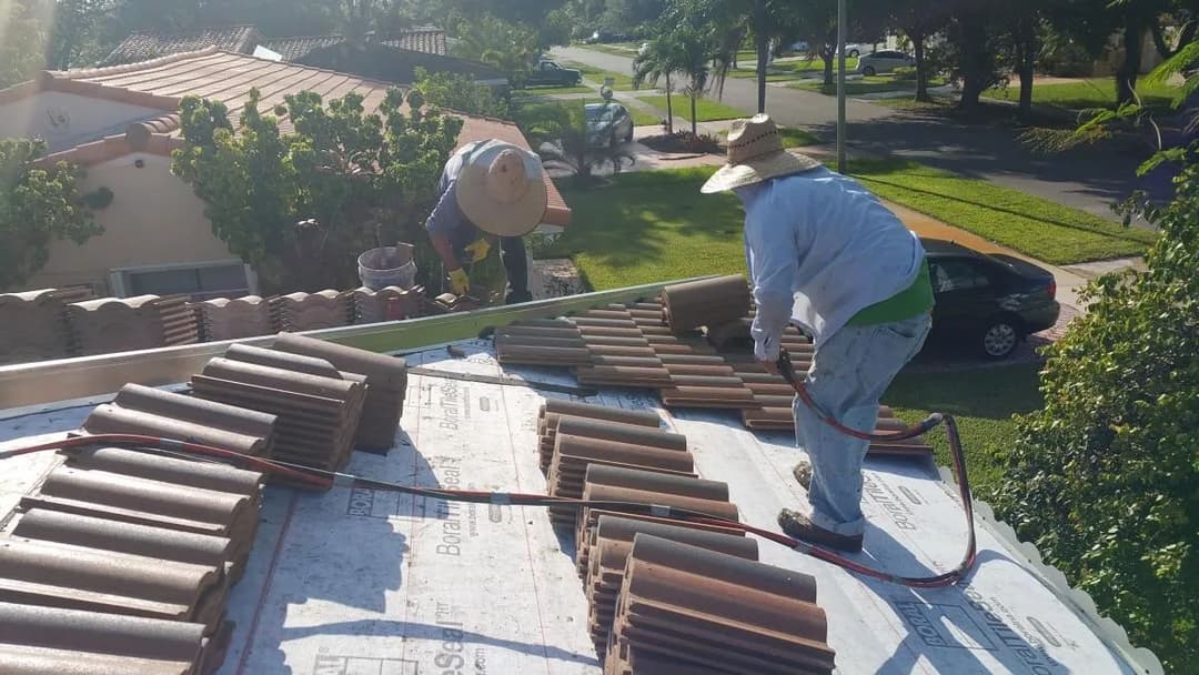 Roofers installing tiles on a home, showcasing roofing work on a sunny day.